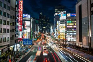 This image showcases a bustling Japanese city street at night, illuminated by numerous neon signs with Japanese characters and some in English like "PROMISE". Cars create streaks of light as they move, and tall buildings line the sides. It relates to the "2025 Facebook Marketing Guide for Japan", hinting at the vibrant market where Facebook can be utilized to reach the active and tech - engaged Japanese audience.
