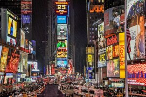 Eine beleuchtete Straßenlandschaft mit zahlreichen Werbeanzeigen in Times Square, New York. Diese lebendige Szene spiegelt die Dynamik der 2025 Globale Influencer - Marketing - Trends wider, in denen die visuelle Präsentation und die Reichweite auf der Weltbühne von großer Bedeutung sind.