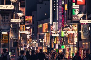 The image captures a vibrant Japanese street teeming with people. Buildings are covered in a plethora of signs, both in Japanese and English, like "ZARA" and "FamilyM". This dynamic urban landscape ties in with the "2025 Snapchat Marketing Guide for Japan", suggesting the rich opportunities to engage Japan's active populace through Snapchat, leveraging the energy and diversity of such lively settings.