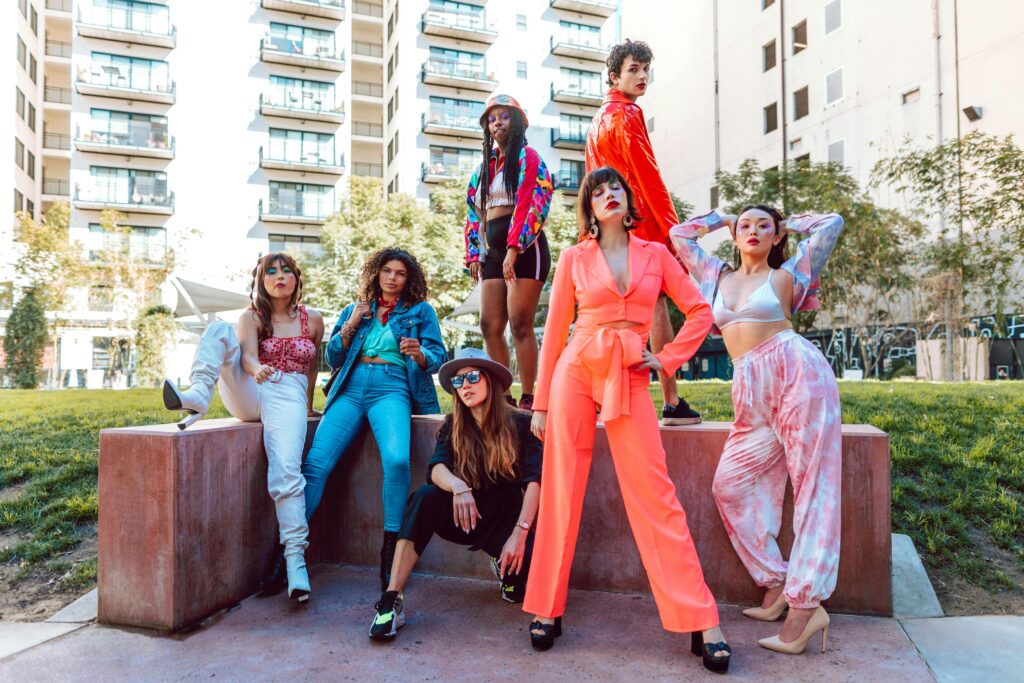 Un grupo de personas con una amplia variedad de estilos de vestir se posan en un espacio al aire libre. Esta imagen representa la diversidad y la creatividad que se espera en las 2025 Tendencias Globales del Marketing de Influenciadores, donde la individualidad y la capacidad de conexión con diferentes audiencias serán claves.