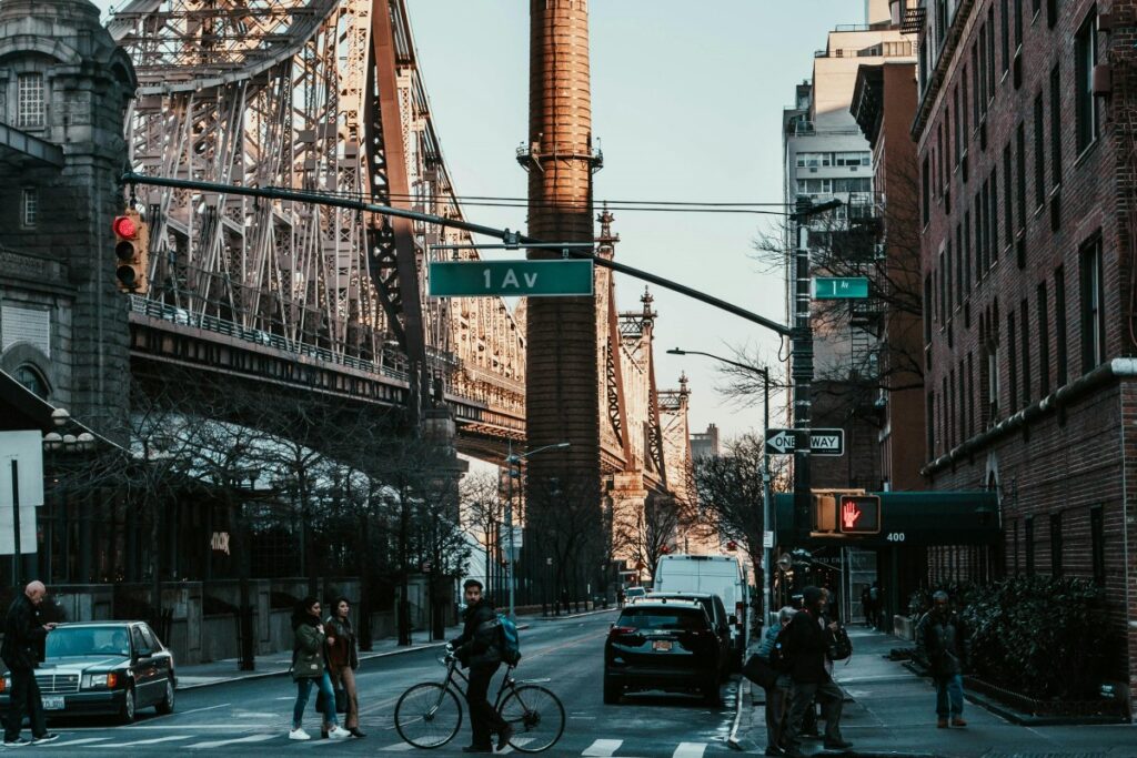 2025年英国Pinterest营销秘籍：在纽约街头，标志性的大桥横跨画面，钢铁结构尽显工业风。1大道的路牌醒目，行人或骑车或漫步，车辆有序停靠，砖红色建筑林立，这里的日常景象充满独特都市魅力 。