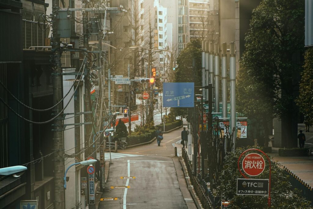 2025年英国Reddit营销秘籍：在日本东京的街道，电线纵横交错，路旁指示牌林立，“渋谷（Shibuya）” 的蓝色路牌尤为显眼。行人和绿植点缀其间，现代建筑错落，这里弥漫着独特的都市烟火气与秩序感 。