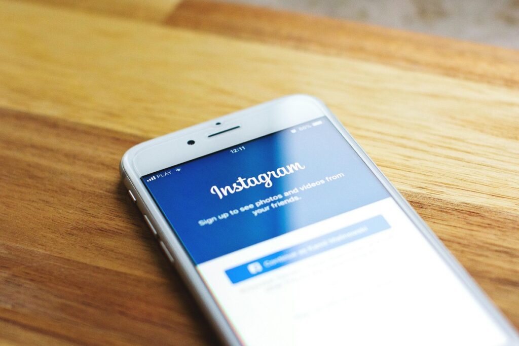 A smartphone lies on a wooden table, its screen displaying the Instagram sign - up page. The text on the screen invites users to sign up to view photos and videos from friends. This image relates to the concept of “Why Instagram Influencers Matter for Your Global Strategy”, suggesting the significance of Instagram in reaching a global audience through influencers.