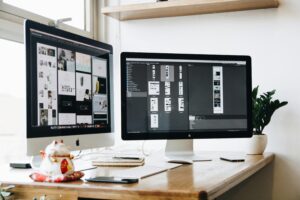 Two computer monitors display content relevant to brand - related activities, perhaps hinting at the decision - making process for global brands when choosing between Xiaohongshu and Douyin. The setup suggests a workspace where one might analyze and compare the two platforms as presented in the topic "Xiaohongshu vs Douyin for Global Brands: Which Platform Should You Choose?"