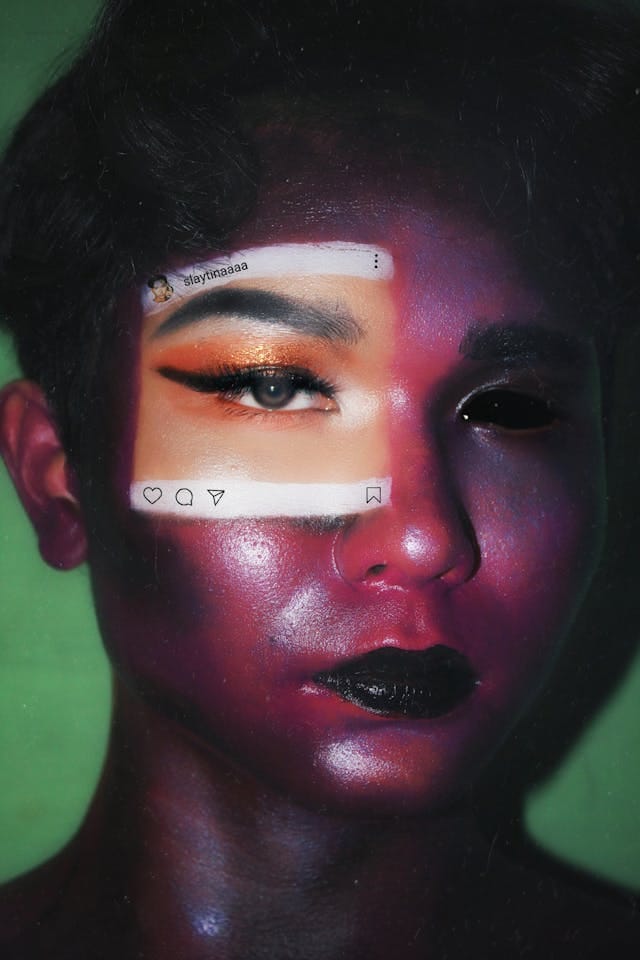 Pessoa com maquiagem artística, mostrando um olho com maquiagem colorida e um quadrado com ícones e um nome de usuário sobre a face, contra um fundo verde.