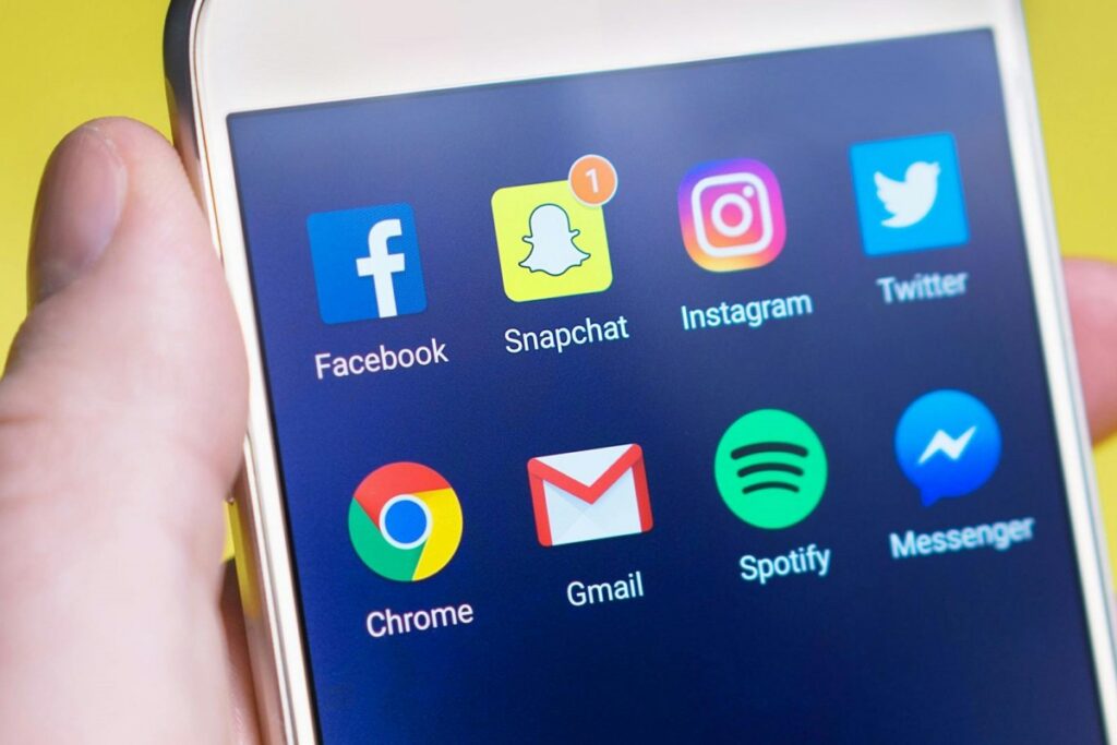 يد تحمل هاتف محكم يظهر على شاشتهرموز التطبيقات الشهيرة مثل Facebook، Snapchat، Instagram، Twitter، Chrome، Gmail، Spotify و Messenger. و في النص: BaoLiba منصة المؤثرين الصغار العالمية لتعزيز نجاح العلامات التجارية