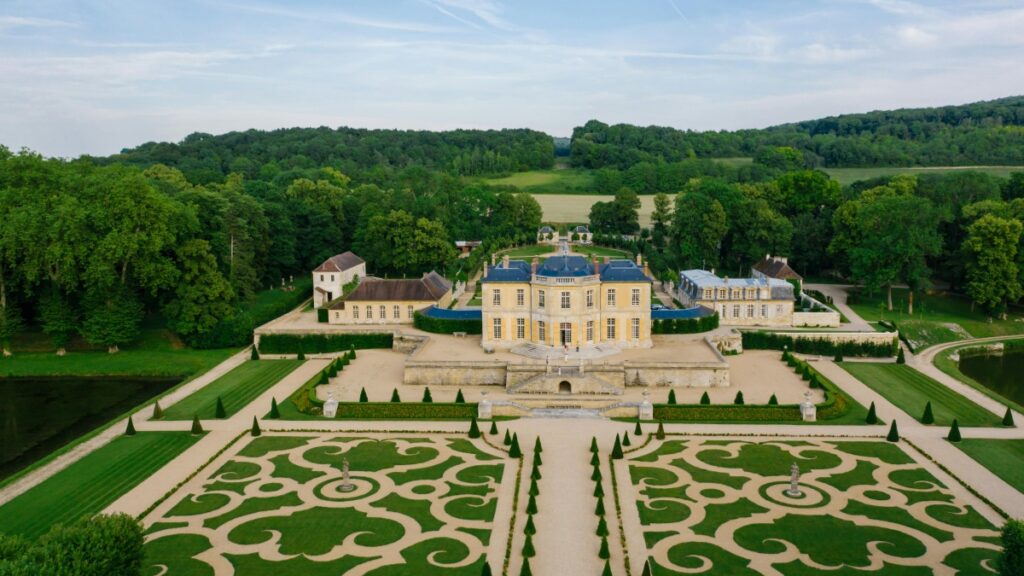 Vue aérienne d'un château magnifique entouré d'un parc paysager soigneusement entretenu. Le château, avec son architecture élégante et ses toits bleus, est au cœur d'un décor verdoyant, avec des allées de cyprès et des jardins à la française. Tout comme ce château incarne le raffinement et la précision dans son agencement, "Comment utiliser ShareChat pour faire du marketing en Inde (vue depuis la France)" offre des pistes pour exploiter avec justesse les opportunités de marketing dans le marché indien.
