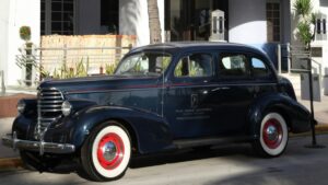 A classic vintage car parked on the street, with a sleek dark - blue body and distinctive red - rimmed white - wall tires. This image is related to the topic "How to Make Money on Signal", perhaps suggesting a connection between the elegance and timelessness of the car and the potential for stable, long - term financial gains through strategies on Signal.