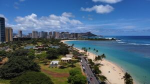 A stunning aerial view of a beachside city with clear blue waters, sandy shores, palm trees, and modern skyscrapers under a partly - cloudy sky. Discover "How to Make Money on Snapchat: Unlock Your Earning Potential" and turn your social media presence into a revenue stream.