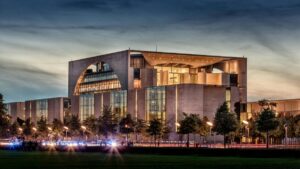 Das Regierungsgebäude in Berlin bei Dämmerung, mit seinem modernen und imposanten Design. Das Gebäude wird von Bäumen umgeben und die Lichter leuchten drinnen. Während man sich dieses beeindruckende Gebäude anschaut, entsteht die Frage: In welchen Ländern sind Likee - Videos noch heiß