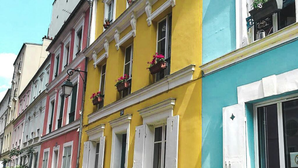 Une rangée de bâtiments colorés, jaune, bleu - ciel, rose et blanc, avec des fleurs dans les vasques des fenêtres. Que devient Dubsmash, l'appli pionnière du lipsync avant TikTok, c'est une question qui suscite l'intérêt.