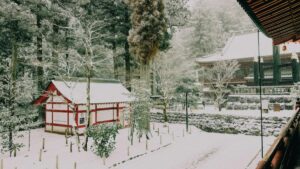 雪に覆われた神社の風景です。白と赤の建物が雪に包まれ、周りの木々も雪を積んでいます。このような美しい風景と同じように、「Tinderでお金を稼ぐには？2025年、日本でのリアルな活用法」を探求することで、新しい収入の機会を見つけることができるかもしれません。