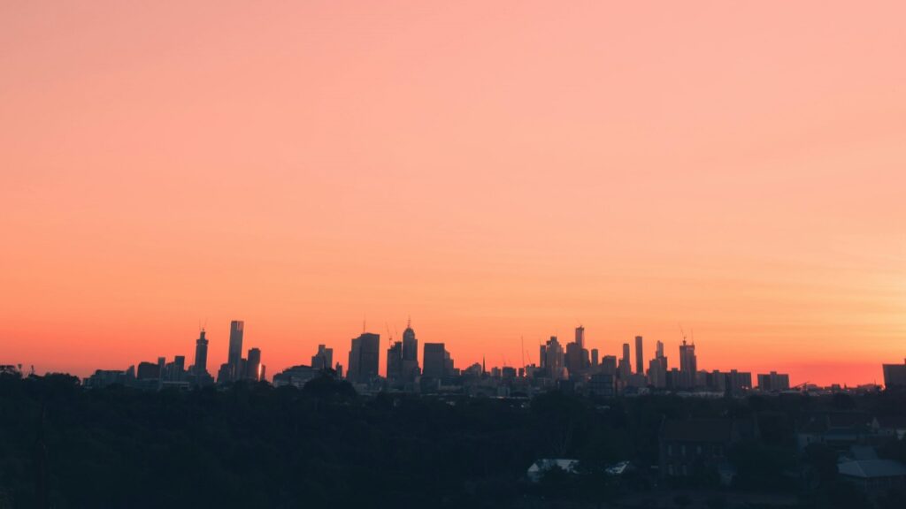 Silhouetted skyscrapers against a vibrant orange sunset sky, creating a picturesque urban scene. Discover more about communication tech with "What Is iMessage and How Is It Different from SMS".