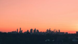 Silhouetted skyscrapers against a vibrant orange sunset sky, creating a picturesque urban scene. Discover more about communication tech with "What Is iMessage and How Is It Different from SMS".