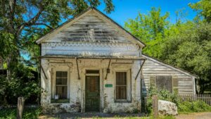 An old, weather - worn wooden building with chipped paint, numbered 1126, surrounded by greenery. Whatever Happened to Dubsmash – The Lip - Sync OG That Walked So TikTok Could Run, this scene evokes a sense of nostalgia similar to the memories of Dubsmash's heyday.