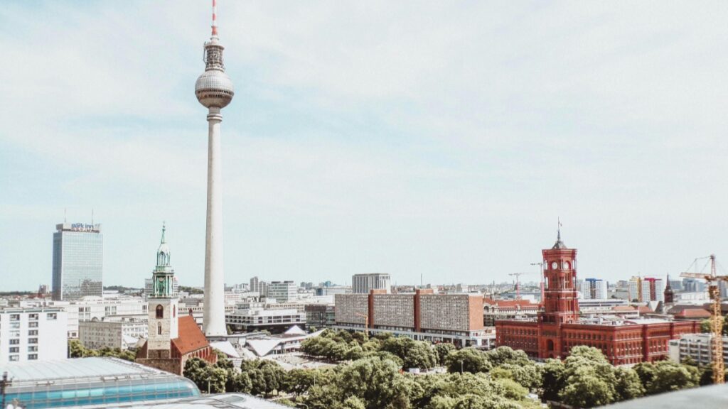 Die Abbildung zeigt die Skyline von Berlin mit dem berühmten Fernsehturm als Hervorhebung. Daneben sind verschiedene Gebäude, wie Kirchen und moderne Hochhäuser zu sehen. Während man sich die wunderschöne Stadtansicht anschaut, ist es auch interessant, sich über die Möglichkeiten zu informieren, Wie man mit Bigo Live Geld verdient, um zusätzliches Einkommen zu erzielen.