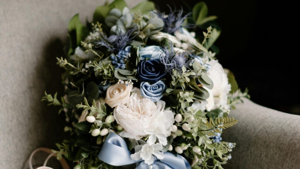 A beautifully arranged bouquet with white and blue flowers and green foliage, placed on a textured surface. This floral arrangement is related to the 2025 Charging Standards for Funimate Influencer Promotions in China, symbolizing elegance and charm in promotional contexts.