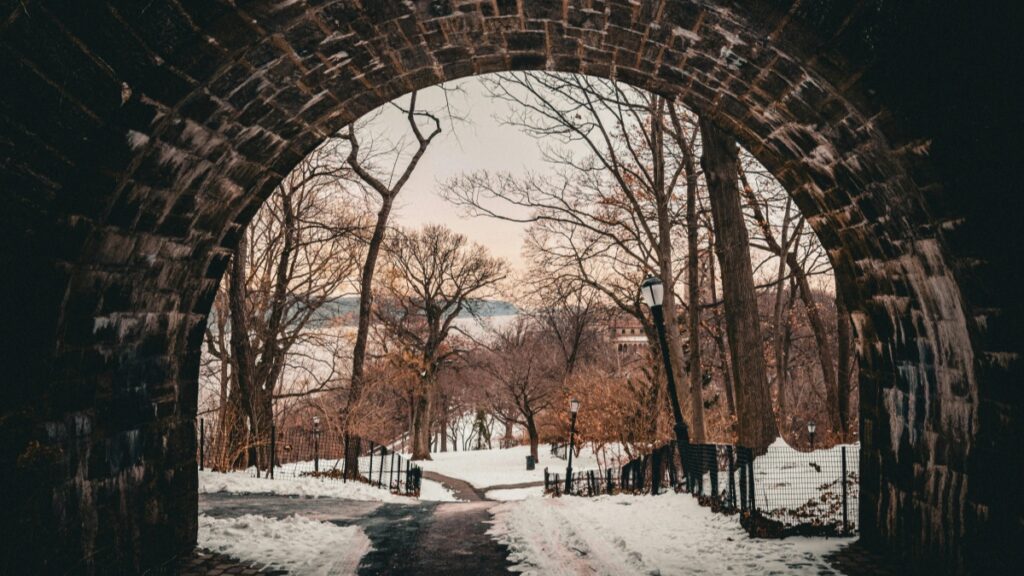 A serene winter scene viewed through a stone archway, with snow - covered paths, leafless trees, and vintage street lamps. This image is associated with the 2025 Charging Standards for Likee Influencer Promotions in the U.S., capturing a tranquil and picturesque setting relevant to influencer marketing contexts.