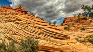 A striking landscape of orange, layered rock formations under a partly cloudy sky, with sparse trees and shrubs dotting the terrain. This image relates to the 2025 Charging Standards for Tinder Influencer Promotions in the U.S., capturing a natural and visually - appealing backdrop relevant to influencer marketing scenarios.