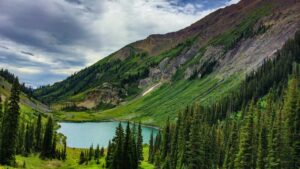 A breathtaking natural landscape featuring a serene alpine lake nestled between lush, forest - covered mountains. The sky above is partly cloudy, adding depth to the scene. This image is associated with the 2025 Charging Standards for Trillerr Influencer Promotions in the U.S., highlighting a picturesque outdoor setting relevant to influencer marketing initiatives.