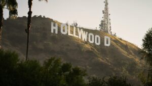 The iconic Hollywood Sign stands prominently on a hillside, surrounded by lush greenery and palm trees. In the background, a communication tower is visible against a soft - lit sky. This image relates to the 2025 Charging Standards for YouTube Influencer Promotions in the U.S., capturing a globally recognized symbol relevant to influencer marketing in the entertainment and digital content space.