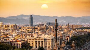 Vue panoramique de Barcelone à la tombée du soleil, avec son incroyable architecture et ses bâtiments emblématiques. Le soleil couchant illumine la ville, tandis que les montagnes dans le lointain ajoutent à la beauté du paysage. Découvrez les 2025 standards de tarification pour les collaborations avec des influenceurs sur Lasso en France.