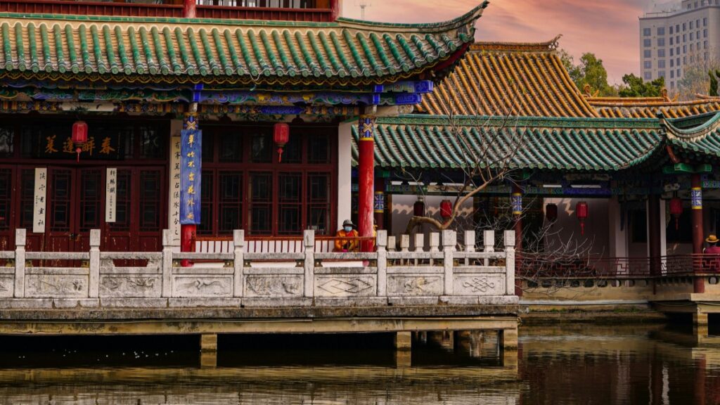 这是一张展示中国传统建筑风格的图片，图中的建筑拥有精美的彩绘和典型的中国式屋顶，屋檐上翘，瓦片呈绿色和蓝色，与红色的柱子形成鲜明对比。建筑前有一片水域，水面平静，反射出建筑的轮廓，增添了一份宁静与和谐。 至于2025年中国Triller网红推广合作收费标准，这可能会根据网红的人气、粉丝活跃度以及推广内容的复杂程度等因素来决定。通常，合作费用可能包括固定费用和基于效果的提成。具体的收费标准需要与网红或其代理机构进行详细咨询和协商，以确保双方都能从合作中获得满意的回报。