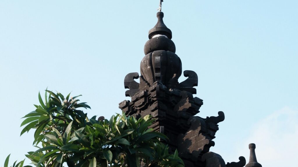 以下是一段包含相关内容的印尼语alt描述： "Atap candi dengan desain tradisional Indonesia, dikelilingi oleh dedaunan hijau. Selain itu, temukan 'Cara Menghasilkan Uang di Vkontakte: Panduan untuk Warga Indonesia' untuk informasi berguna tentang pendapatan online."