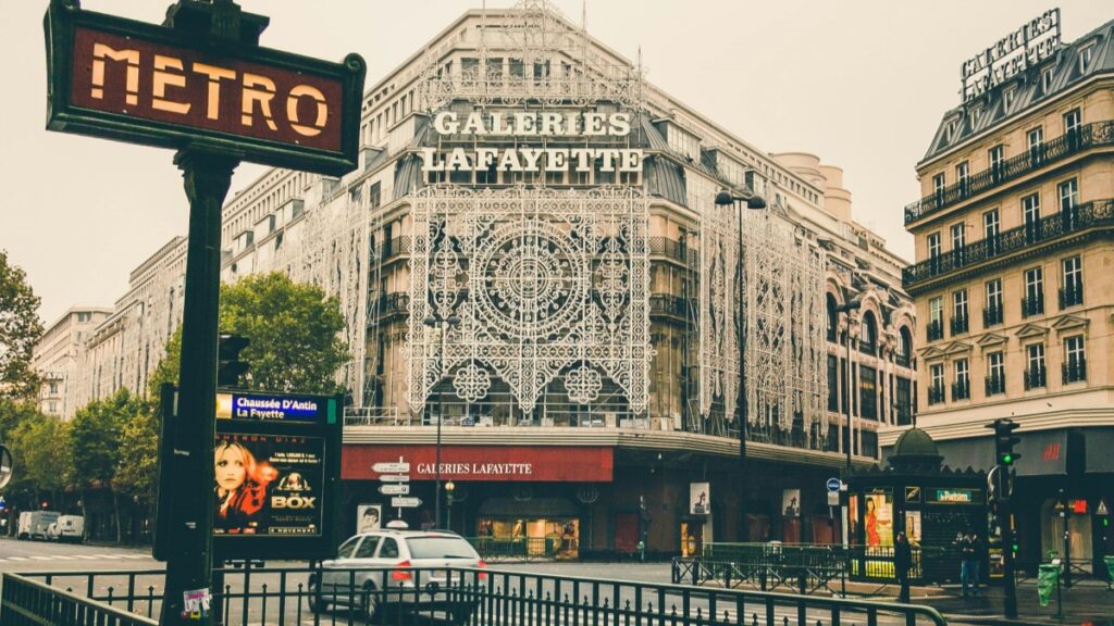 Dans cette image, on voit l'édifice emblématique des Galeries Lafayette à Paris, avec son nom affiché en lettres grandes et lumineuses. Un panneau de métro est visible à gauche, indiquant l'accès au réseau parisien. Pour les professionnels du marketing français intéressés par les tendances des applications de messagerie, l'étude "Quels pays utilisent principalement Viber ? Analyse pour le marché français" offre des informations précieuses.