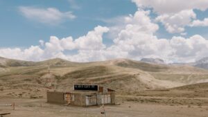 Rumah sederhana yang berdiri di tengah lahan dataran tinggi dengan latar belakang gunung dan awan. Tempat ini menawarkan pemandangan menakjubkan yang bisa menjadi incaran bagi influencer. Terkait dengan Standar Biaya Kerja Sama Influencer di Tinder 2025 di Indonesia, lokasi seperti ini bisa menjadi ide inspiratif untuk membuat konten yang menarik.