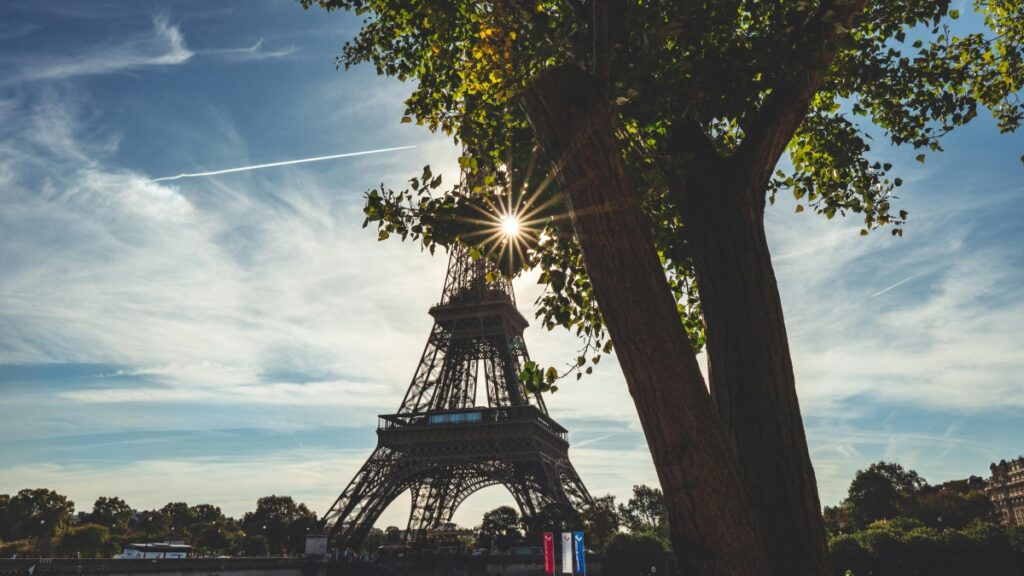 Une vue emblématique de la Tour Eiffel à Paris, baignée par le soleil, avec des arbres en avant - plan. Cette image est associée aux Tarifs de Collaboration avec des Influenceurs sur Tinder en France en 2025.