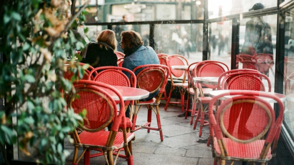 Un café parisien avec des chaises rouges et des clients,illustrant la vitalité de la vie urbaine.Tarifs de Collaboration avec les Influenceurs Facebook en France en 2025.