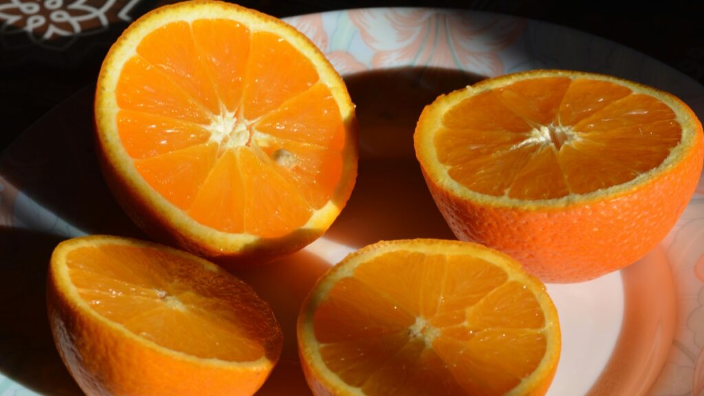 Quatre demi - oranges d'un orange vif, présentées sur une assiette ornée. Découvrez les tarifs de collaboration avec les influenceurs iMessage en France en 2025.
