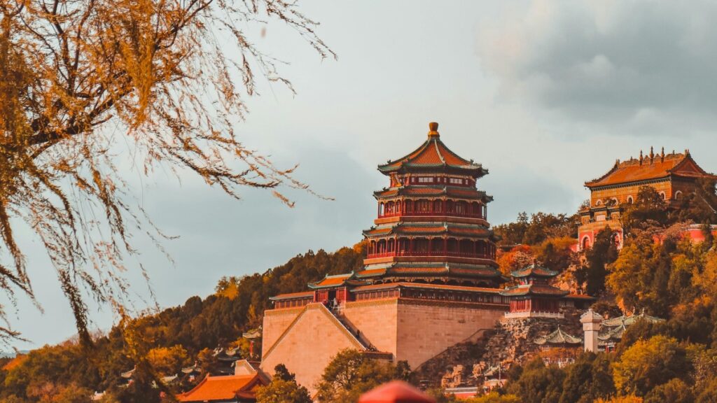 画面中是一座古色古香的中式建筑，红墙绿瓦，飞檐斗拱，错落有致地坐落在山坡上，周围树木的枝叶染上了秋意。对于关注视频社交平台的朋友来说，了解“Vigo Video：TikTok的长兄弟” ，能帮助您知晓相关平台的发展脉络与特色。
