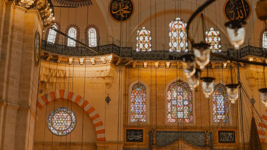 هذه الصورة تظهر الجزء الداخلي من مسجد مذهل، بتصاميم الزجاج الملونة الشهيرة والزخارف الفنية المتقاربة. نجد نافذة كبيرة في وسط الجدار، مُحَدَّدة بزخارف رائعة، وستائر أخرى بتصاميم مذهلة تحرر اللون في جميع أنحاء المكان. هناك أيضًا لوحات إسلامية تُعطِي المكان لمسة روحية. علاوة على ذلك، اكتشف "كيفية كسب المال على ترلر: دليل عملي للمبدعين في المملكة العربية السعودية" لتحقيق المزيد من الإيرادات من وسائل التواصل الاجتماعي.