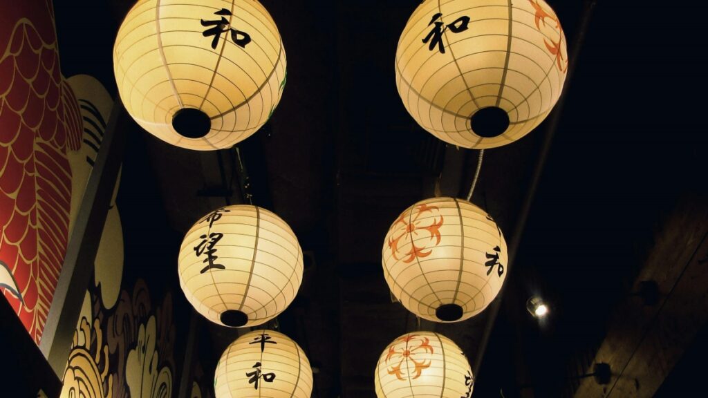 暗い空間に浮かぶ和風提灯。提灯には「和」「希望」「平和」などの文字や、紅葉柄が飾られており、日本の伝統的な美意識が感じられます。2025年日本Lassoインフルエンサー推奨協力料金基準は、このような日本の文化的な風景とともに、現代のメディアビジネスの側面を反映しています。